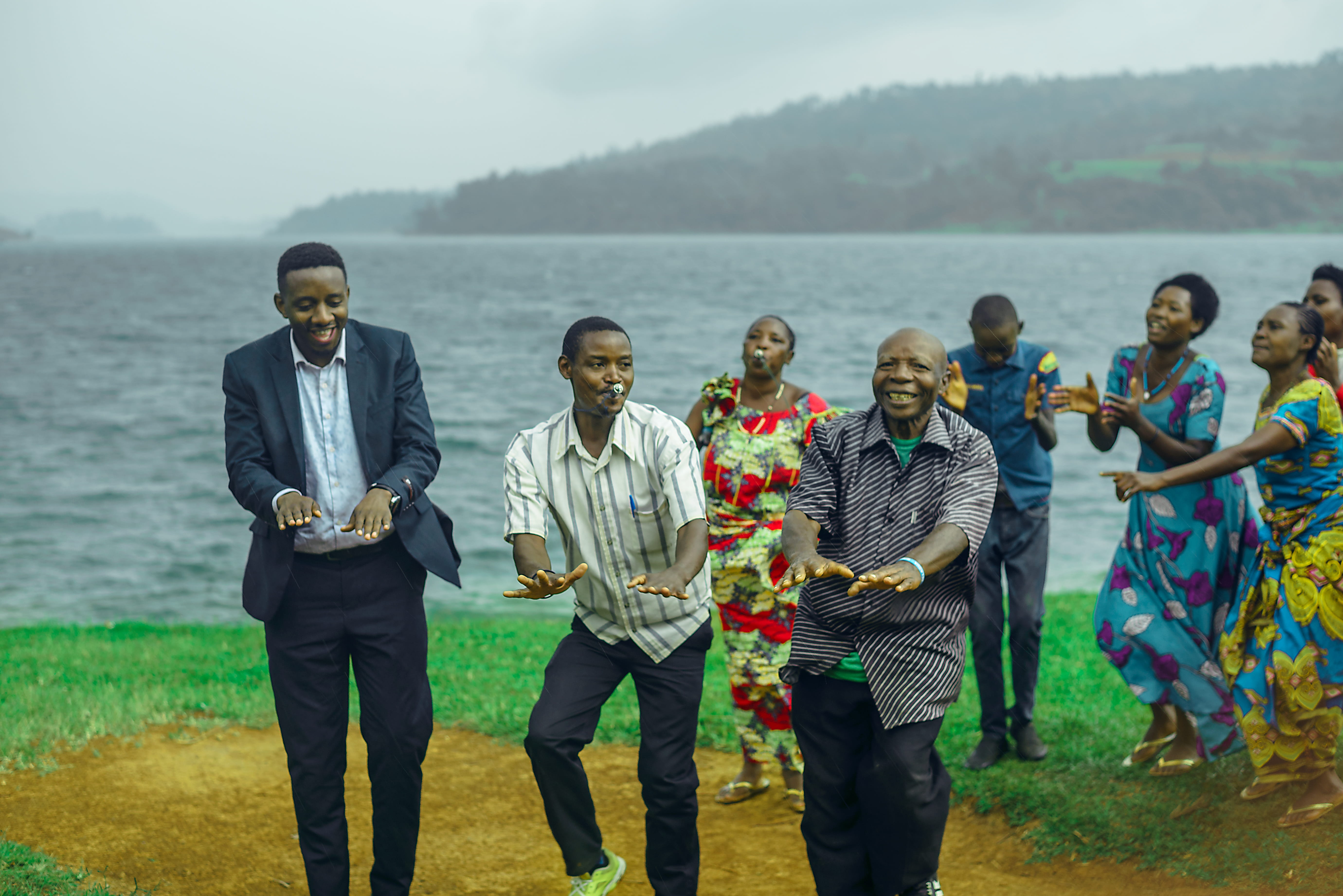 Different generations dancing together beside a lake in Rwanda